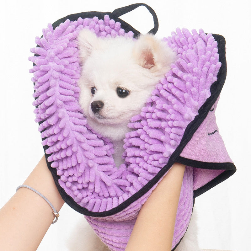 Small white dog inside a purple chenille towel held by a person
