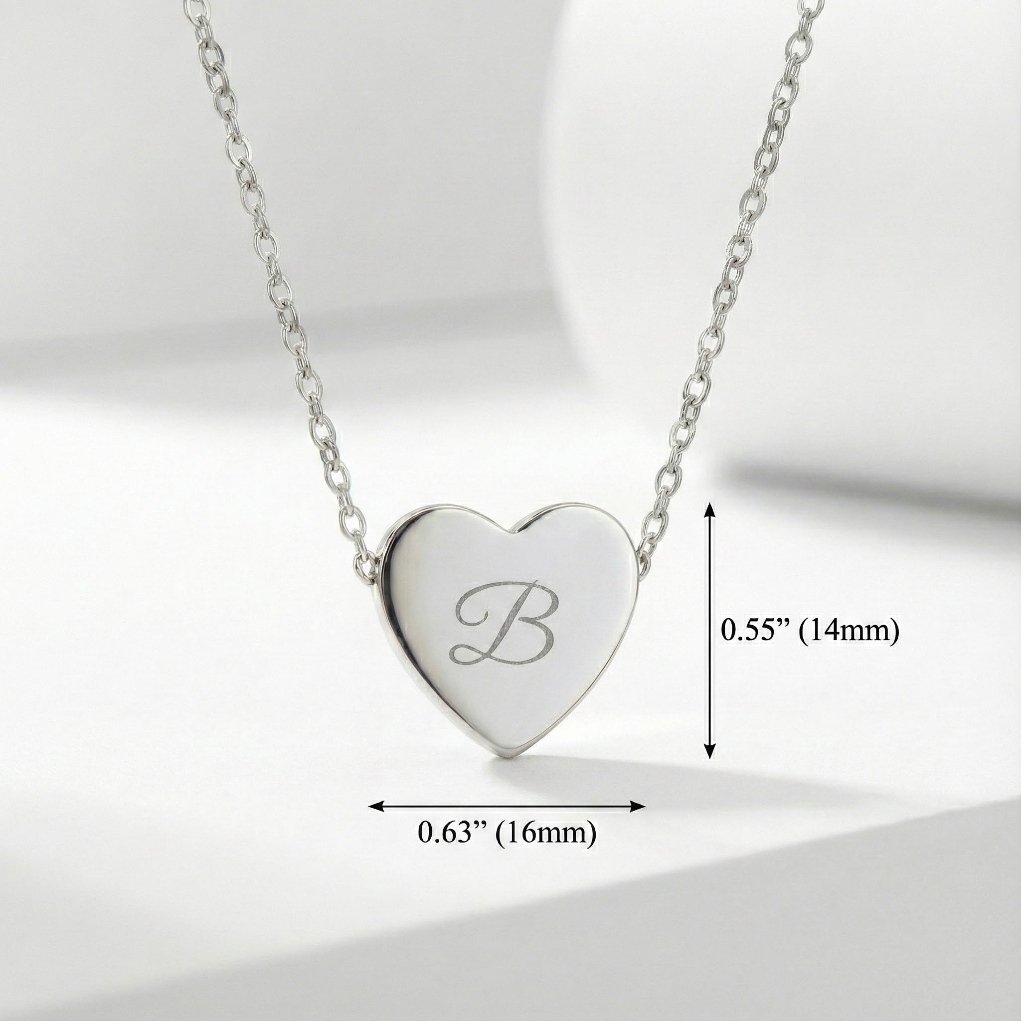 Silver heart-shaped necklace with engraved letter 'B' on a light gray background